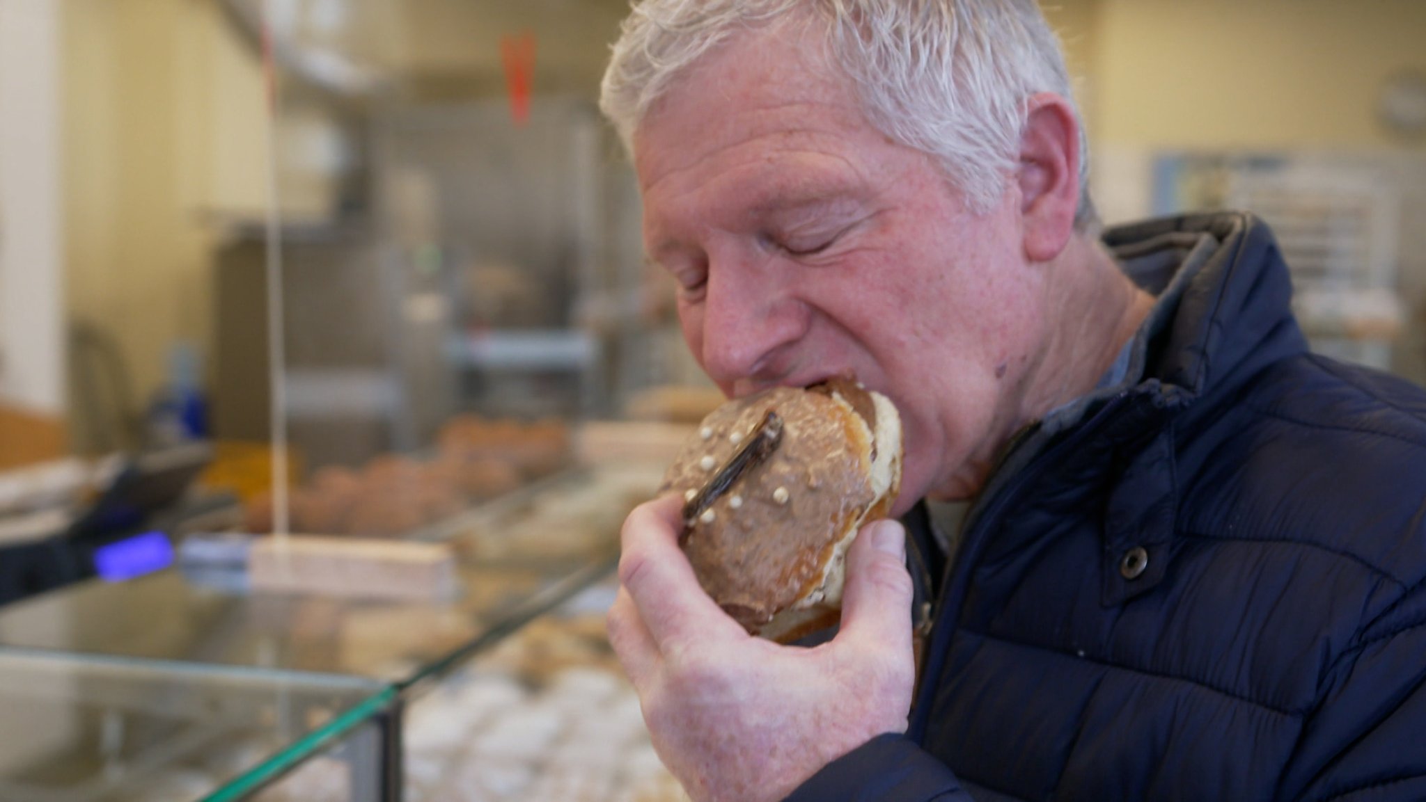 Ein Mann beißt in einen Krapfen mit einem Insekt darauf.