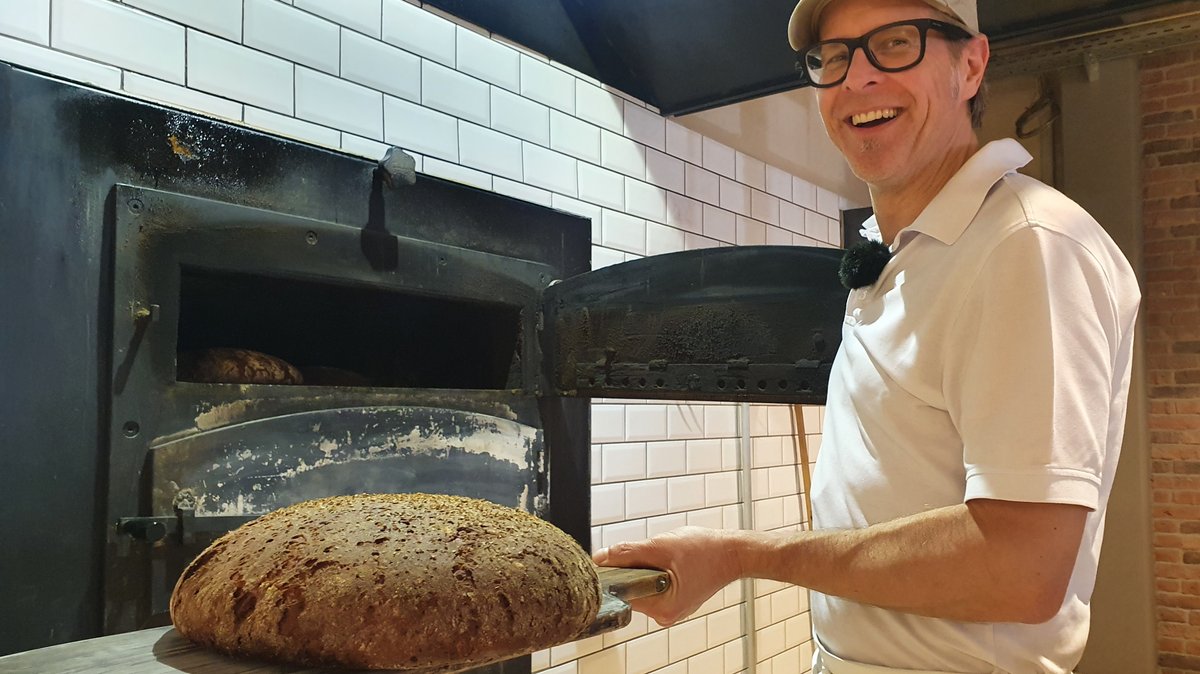 Bäcker Max Kuttenreich hält ein Steinofenbrot in der Hand. 