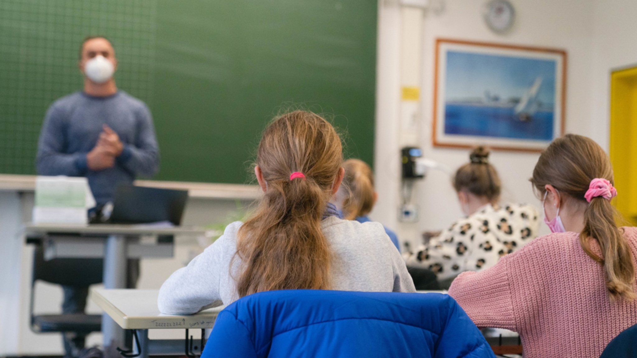 Schülerinnen und Schüler mit Mund-Nasen-Schutz im Klassenzimmer. 