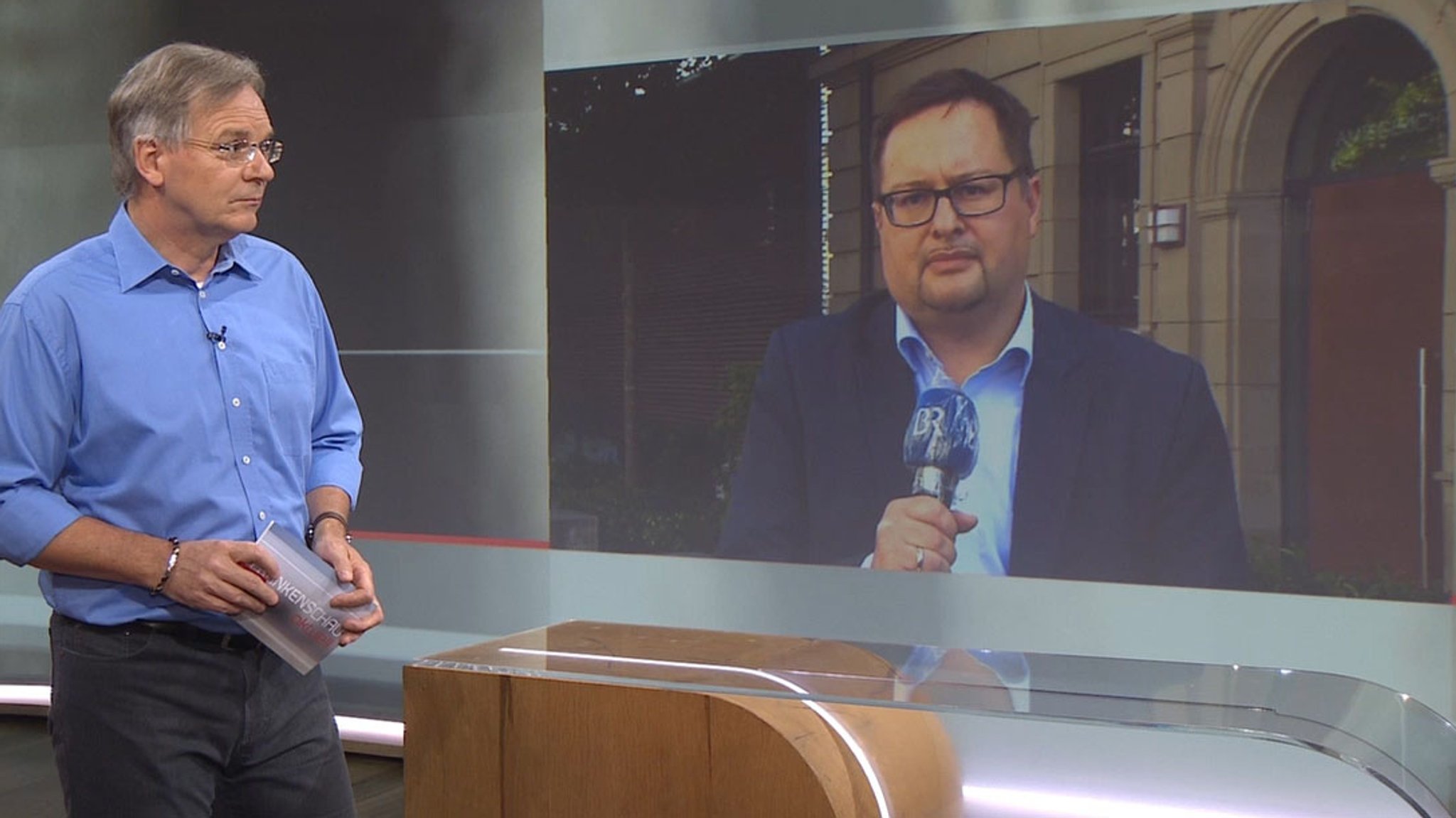 Moderator Charly Hilpert spricht mit Reporter Christian Wölfl vor dem Amtsgericht Bad Kissingen.