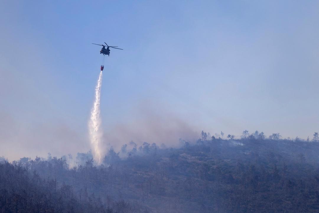 29.06.2024, Griechenland, Katsimidi: Ein Chinook-Hubschrauber wirft Wasser auf einen Waldbrand auf dem Berg Parnitha ab.