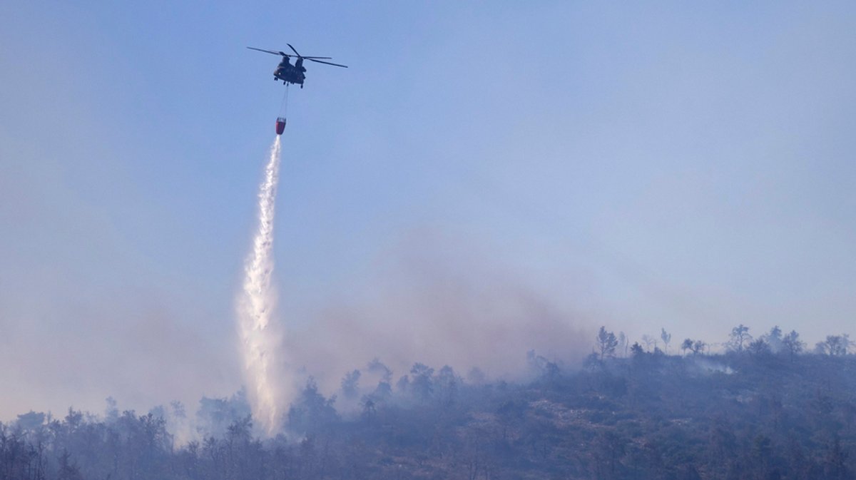 29.06.2024, Griechenland, Katsimidi: Ein Chinook-Hubschrauber wirft Wasser auf einen Waldbrand auf dem Berg Parnitha ab.