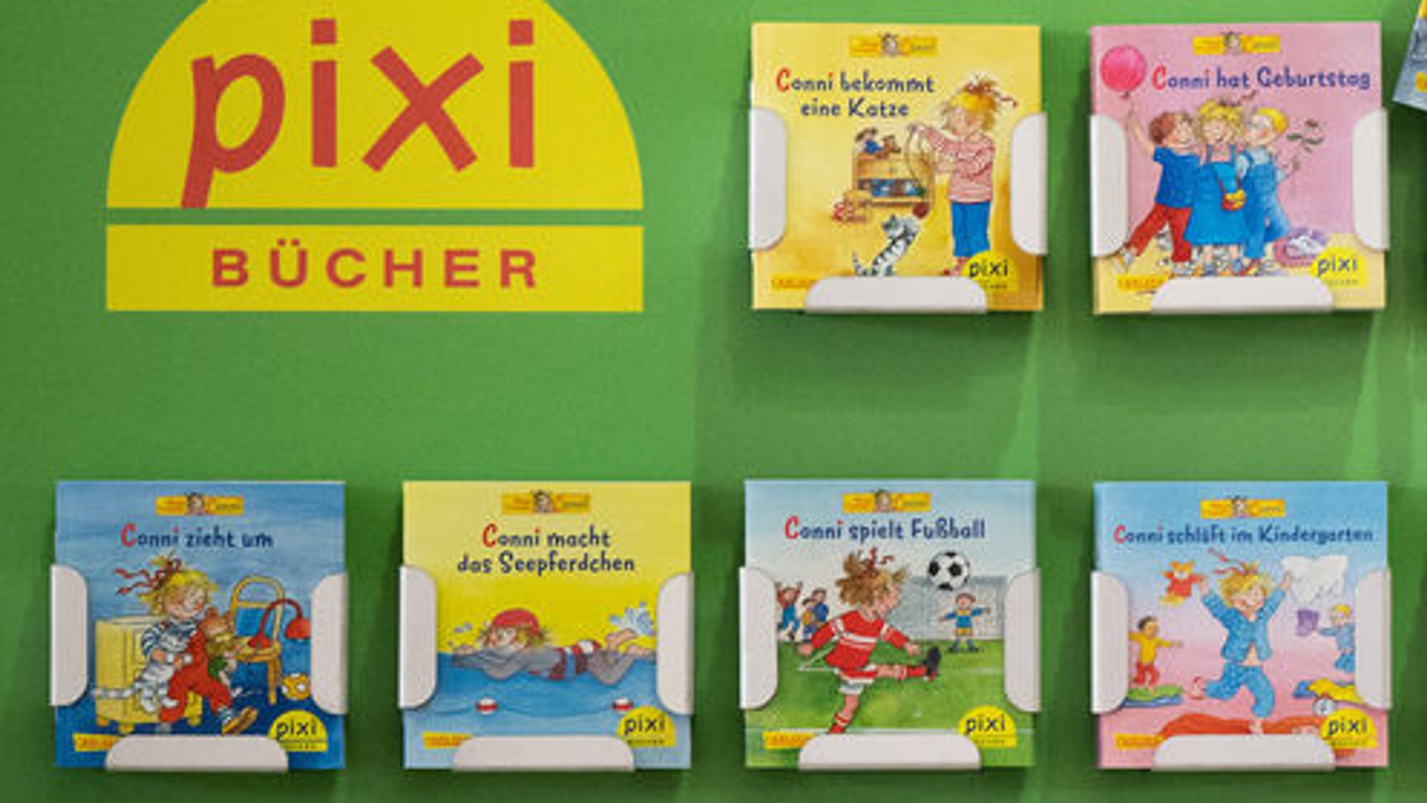 Ein Mann räumt pixi Kinderbücher in ein Regal 