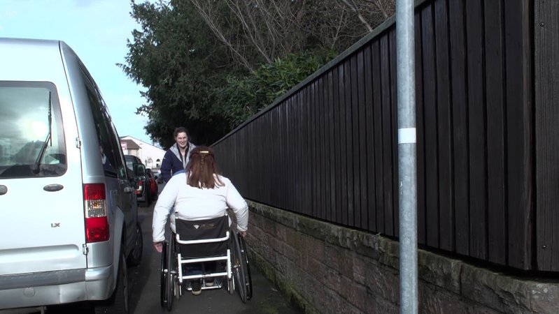 Eine Rollstuhlfahrerin fährt einer anderen Frau in einem engen Gehsteig entgegen. | Bild: BR Eine Rollstuhlfahrerin fährt einer anderen Frau in einem engen Gehsteig entgegen.