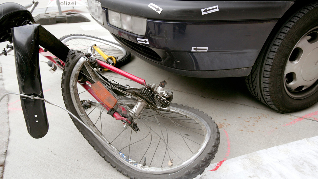 Ein zerdrücktes Fahrrad vor einem Auto