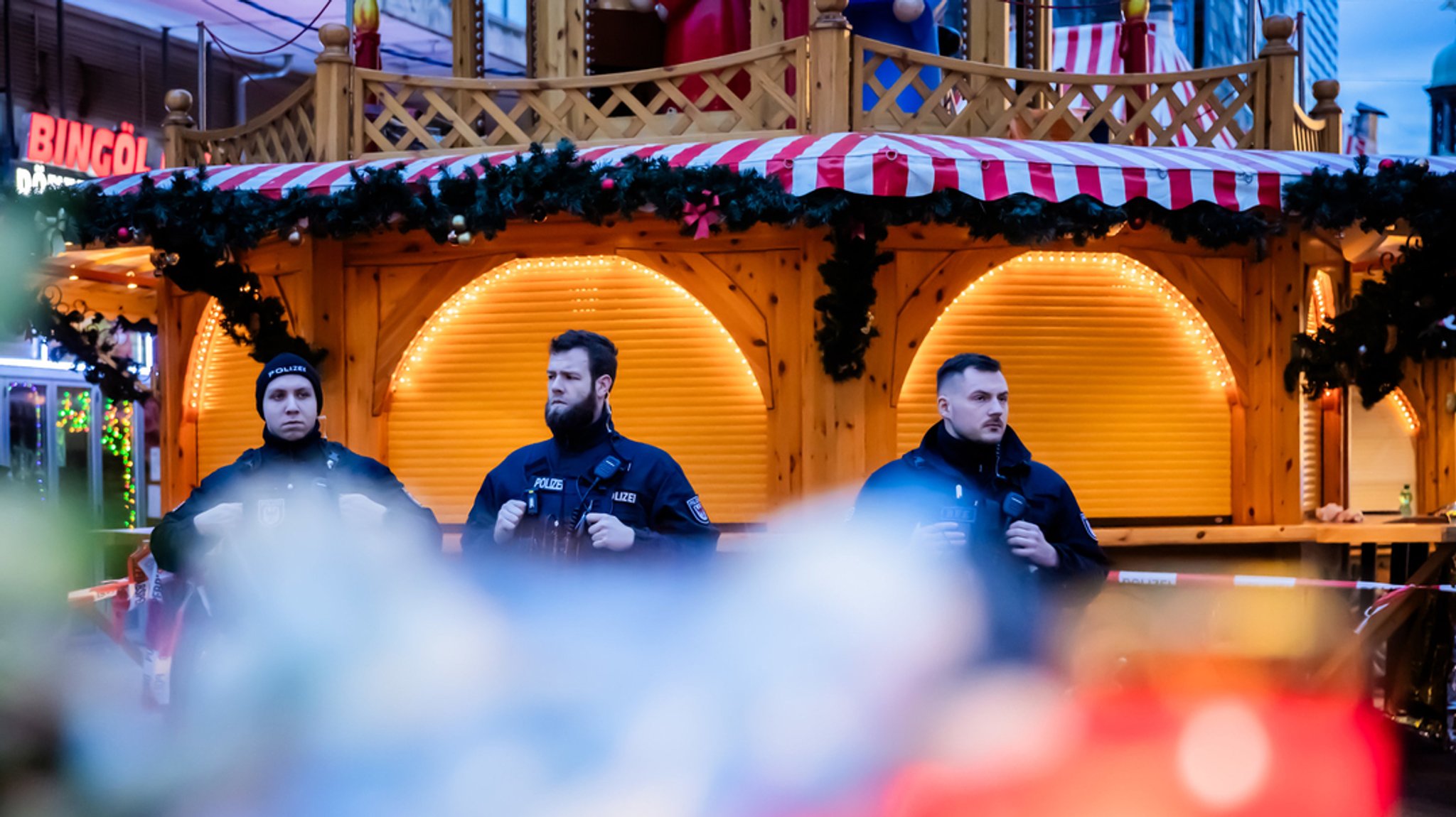 drei bewaffnete Polizisten stehen in Magdeburg vor der Weihnachtspyramide. Einer der Toten nach der Attacke auf den Weihnachtsmarkt in Magdeburg ist ein neunjähriger Bub aus Bayern.