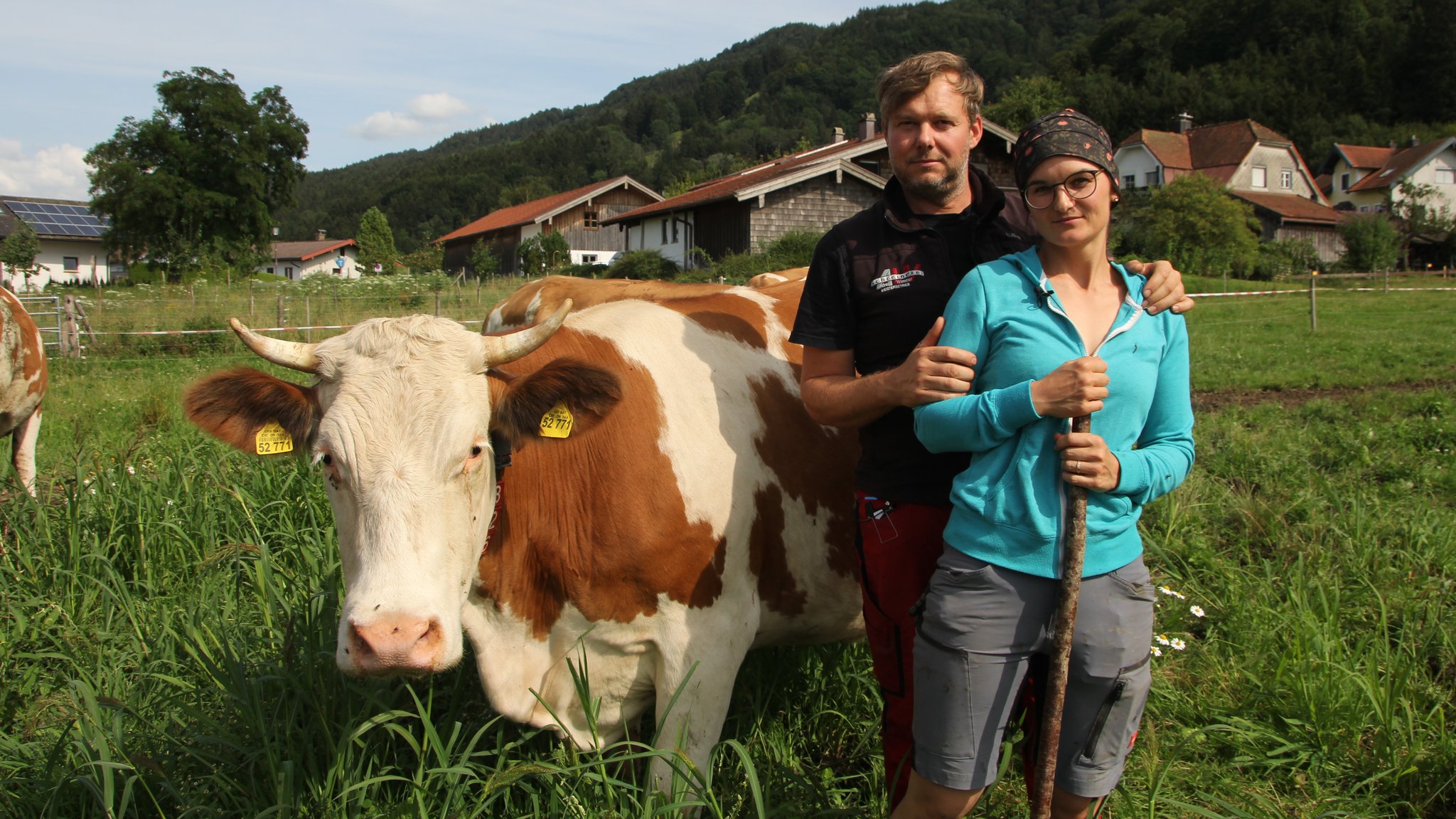 Katharina und Andreas Wimmer auf der Weide neben einer Kuh mit Hörnern