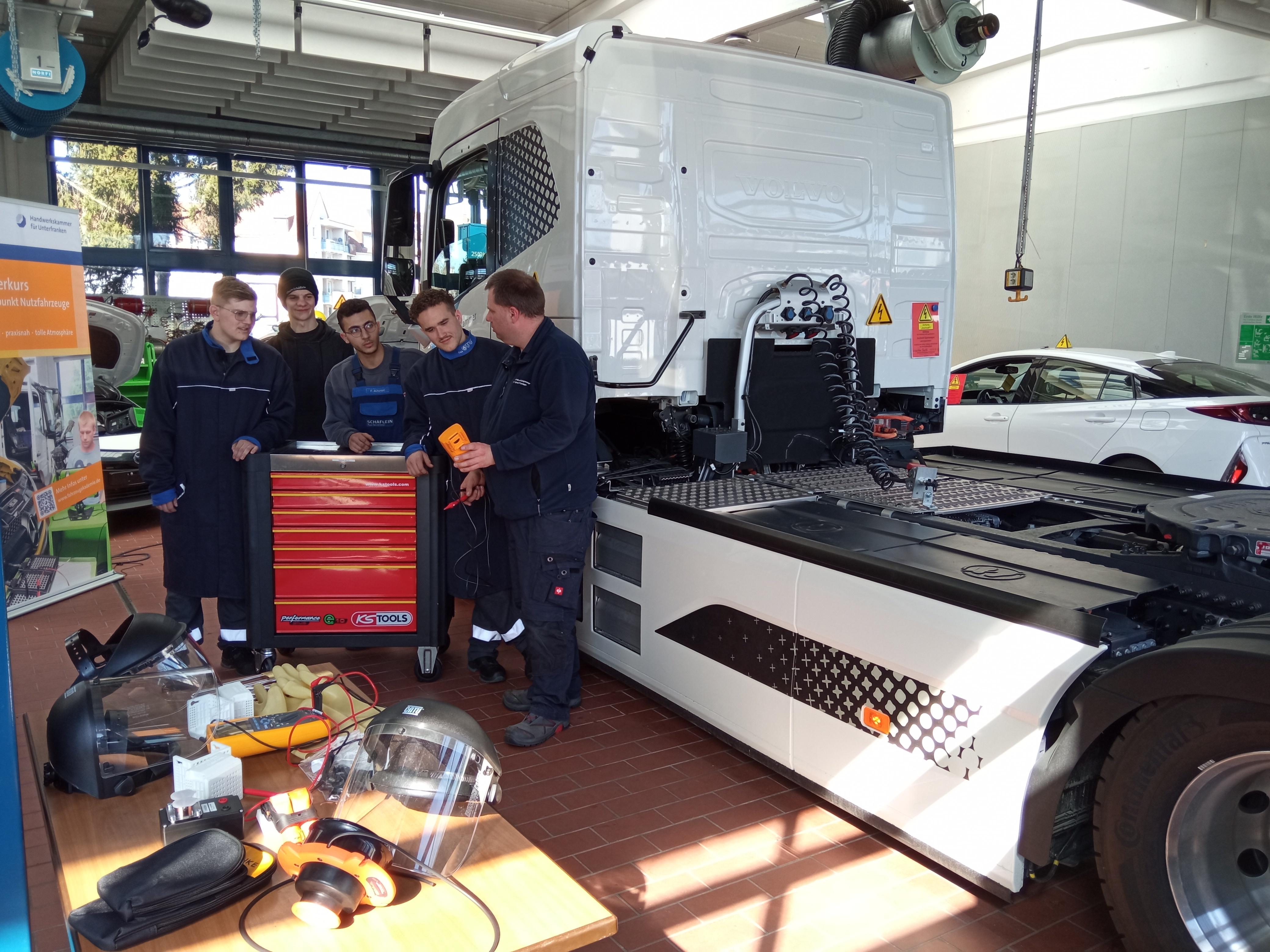 Ausbilder Sebastian Barth weist seine Azubis am E-Lkw in einer Werkstatt der Fahrzeugakademie Schweinfurt ein.