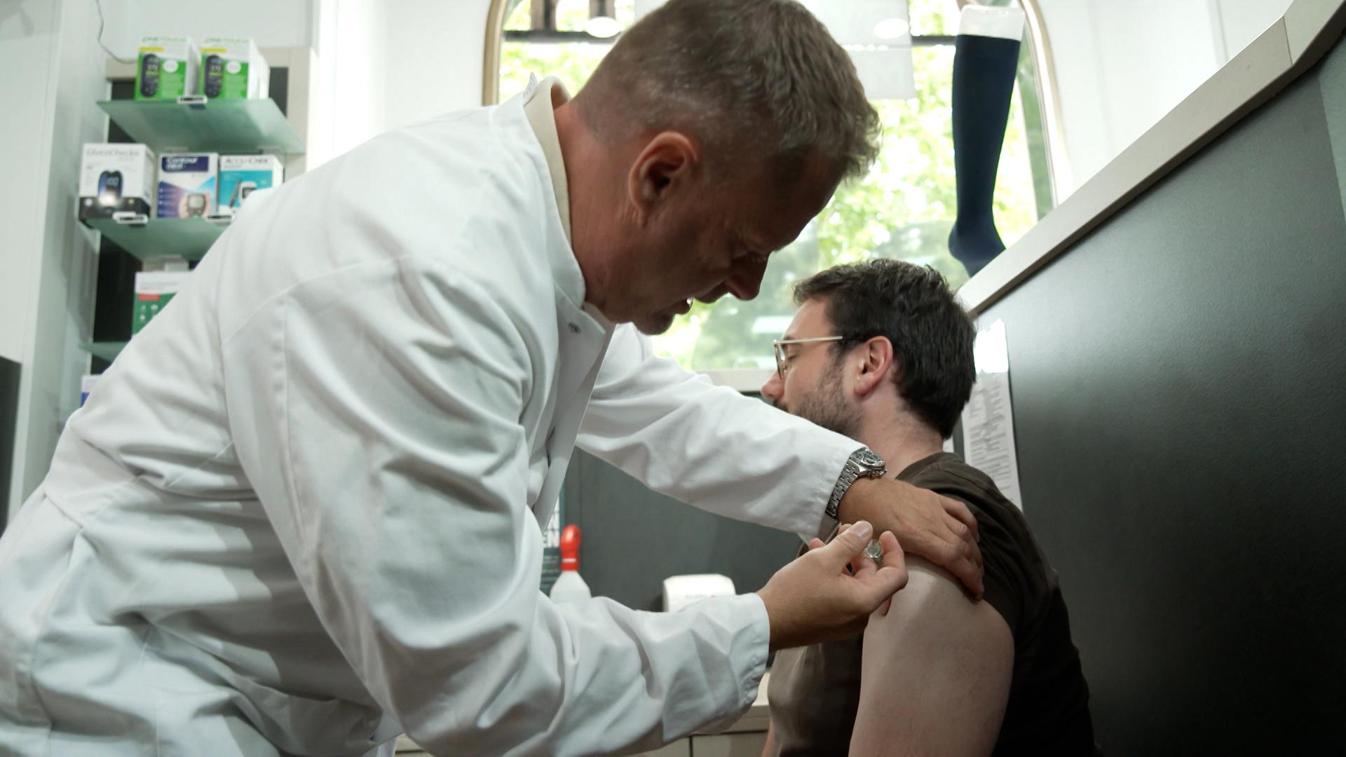 Ein Arzt gibt einem Mann eine Spritze in den Arm