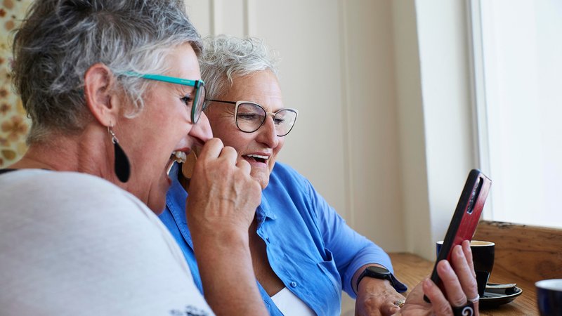 Zwei Frauen sehen auf ein Handy und lachen. | Bild: picture alliance / Westend61 | Luka Storm Zwei Frauen sehen auf ein Handy und lachen.
