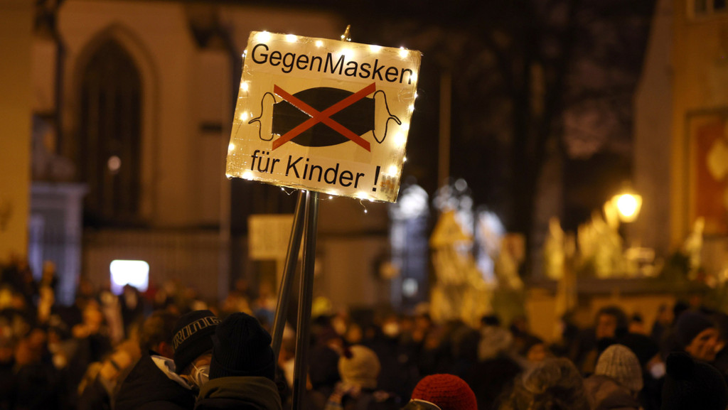 Teilnehmer einer Demonstration gegen die Corona-Maßnahmen am 18.12.21 in Augsburg halten ein Plakat mit der Aufschrift "Gegen Masken für Kinder" hoch (Symbolbild)