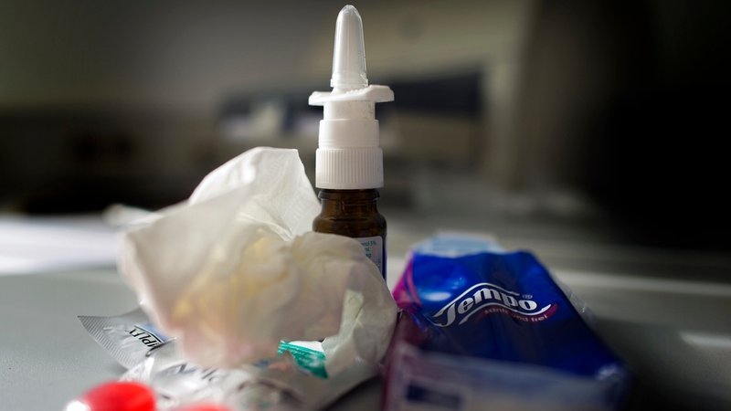 Mittel gegen Erkältung wie Nasenspray, Halstabletten und Papiertaschentücher liegen auf einem Tisch