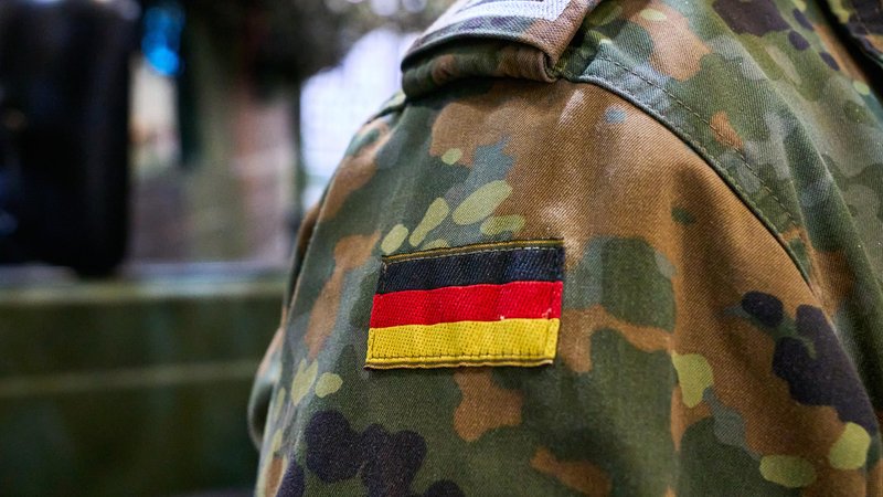 Ein Bundeswehrsoldat in Tarnuniform mit der deutschen Flagge als Abzeichen auf der Schulter. | Bild: picture alliance / CHROMORANGE | Michael Bihlmayer Ein Bundeswehrsoldat in Tarnuniform mit der deutschen Flagge als Abzeichen auf der Schulter.