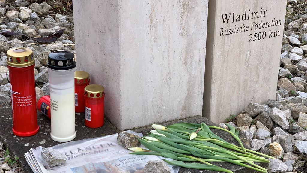 Kerzen und Blumen liegen unter dem Denkmal der Städtepartnerschaft Erlangen - Wladimir.