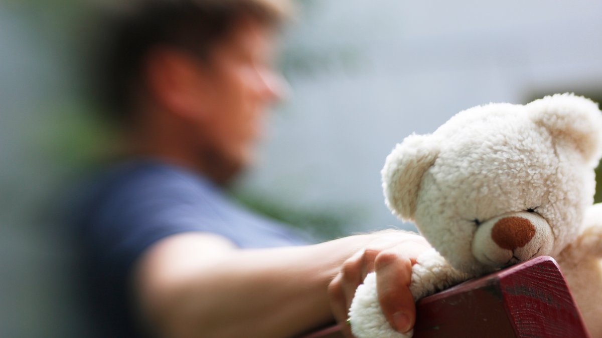 Verlassener Vater hält einen Teddy in der Hand (Symbolbild)