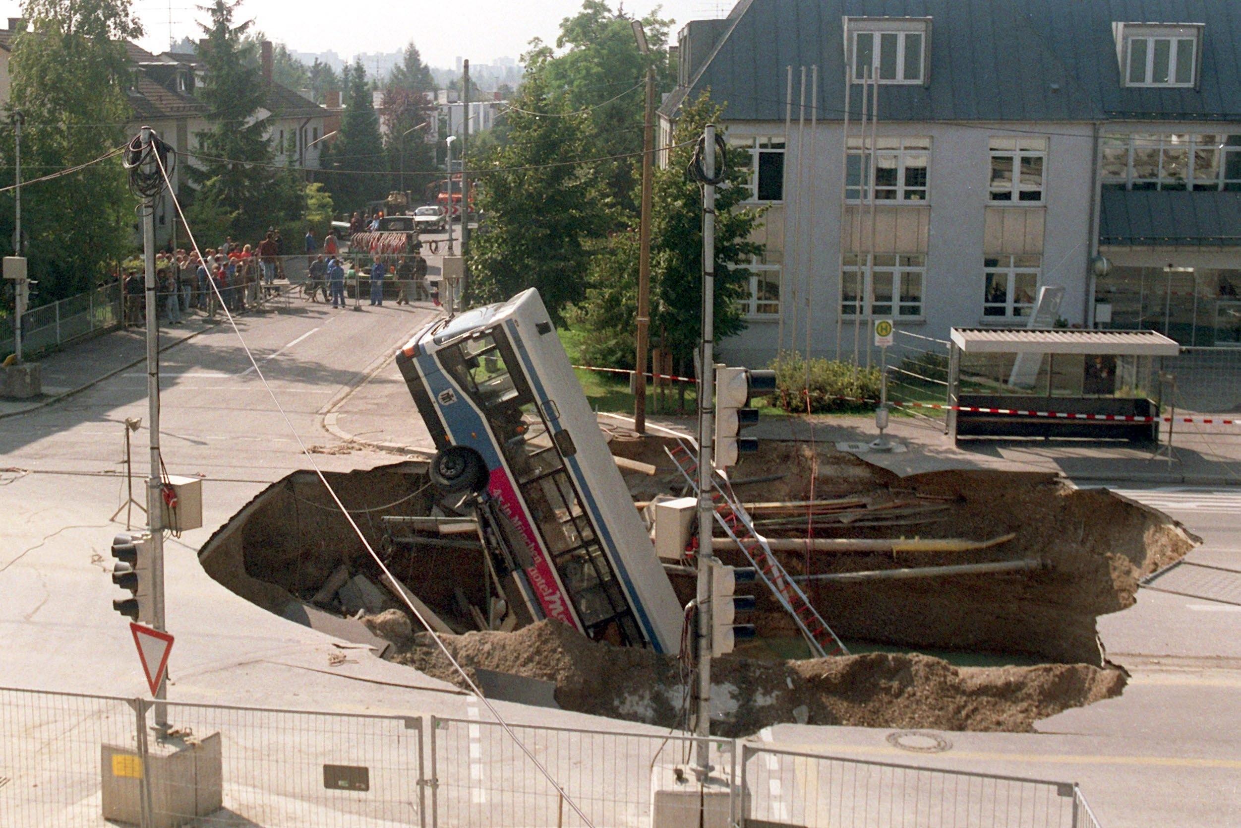 Ein Linienbus steckt in einem riesigen Krater, der sich auf einer Straße im Münchener Stadtteil Trudering aufgetan hat (Archivbild vom 21.9.1994).