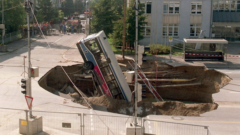 Ein Linienbus steckt in einem riesigen Krater, der sich auf einer Straße im Münchener Stadtteil Trudering aufgetan hat (Archivbild vom 21.9.1994). | Bild: Frank Mächler/dpa Ein Linienbus steckt in einem riesigen Krater, der sich auf einer Straße im Münchener Stadtteil Trudering aufgetan hat (Archivbild vom 21.9.1994).