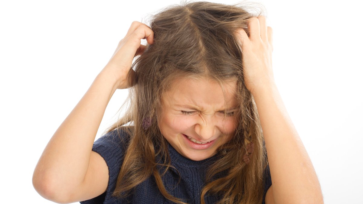 Ein Mädchen mit langen mittelblonden Haare und blauem Pulli kratzt sich mit beiden Händen den Kopf. Das Gesicht ist verzerrt.