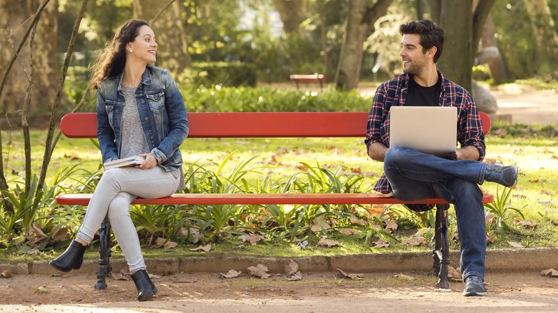 Frühlingsgefühle? Ein Mann und eine Frau flirten auf einer Parkbank.