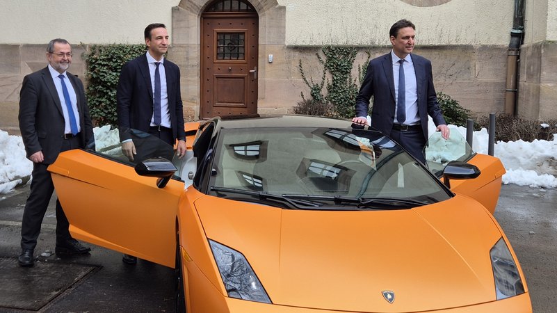 Drei Männer stehen um einen orangefarbenen Sportwagen. | Bild: BR/Martin Hähnlein Drei Männer stehen um einen orangefarbenen Sportwagen.