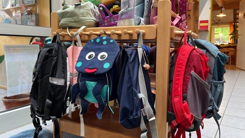 Bunte Kinderrucksäcke hängen in der Garderobe des Kindergartens "Zum Regenbogen" in Willing 