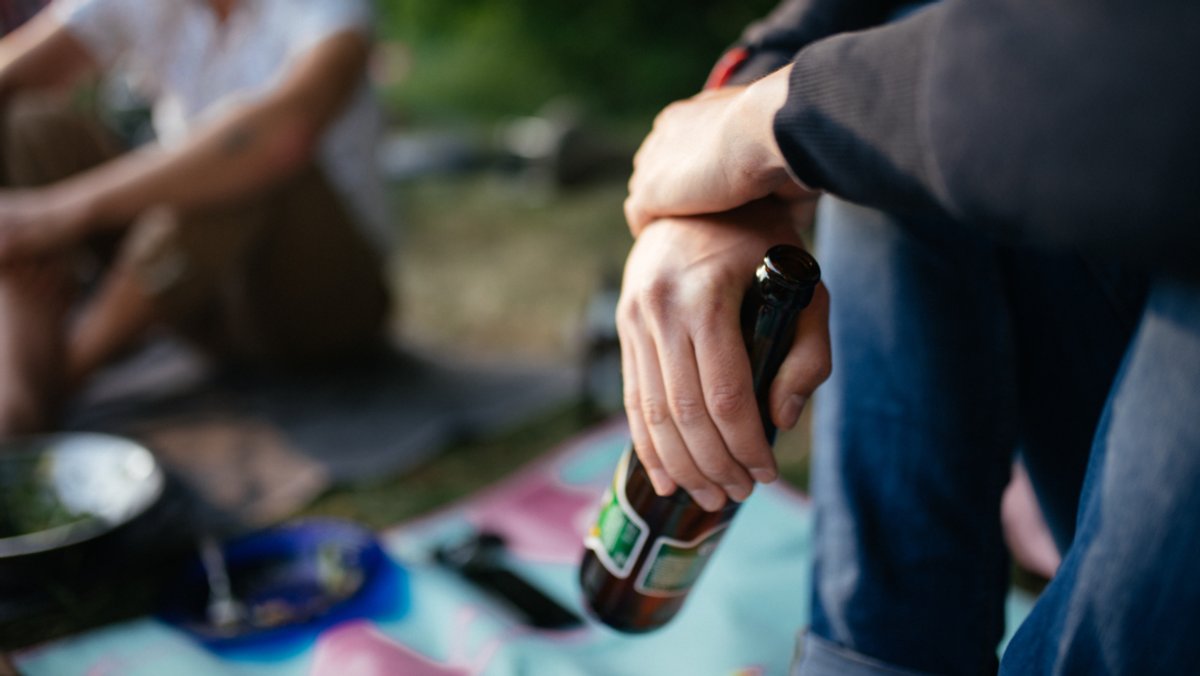Ein junger Mann mit einer Bierflasche (Symbolbild)