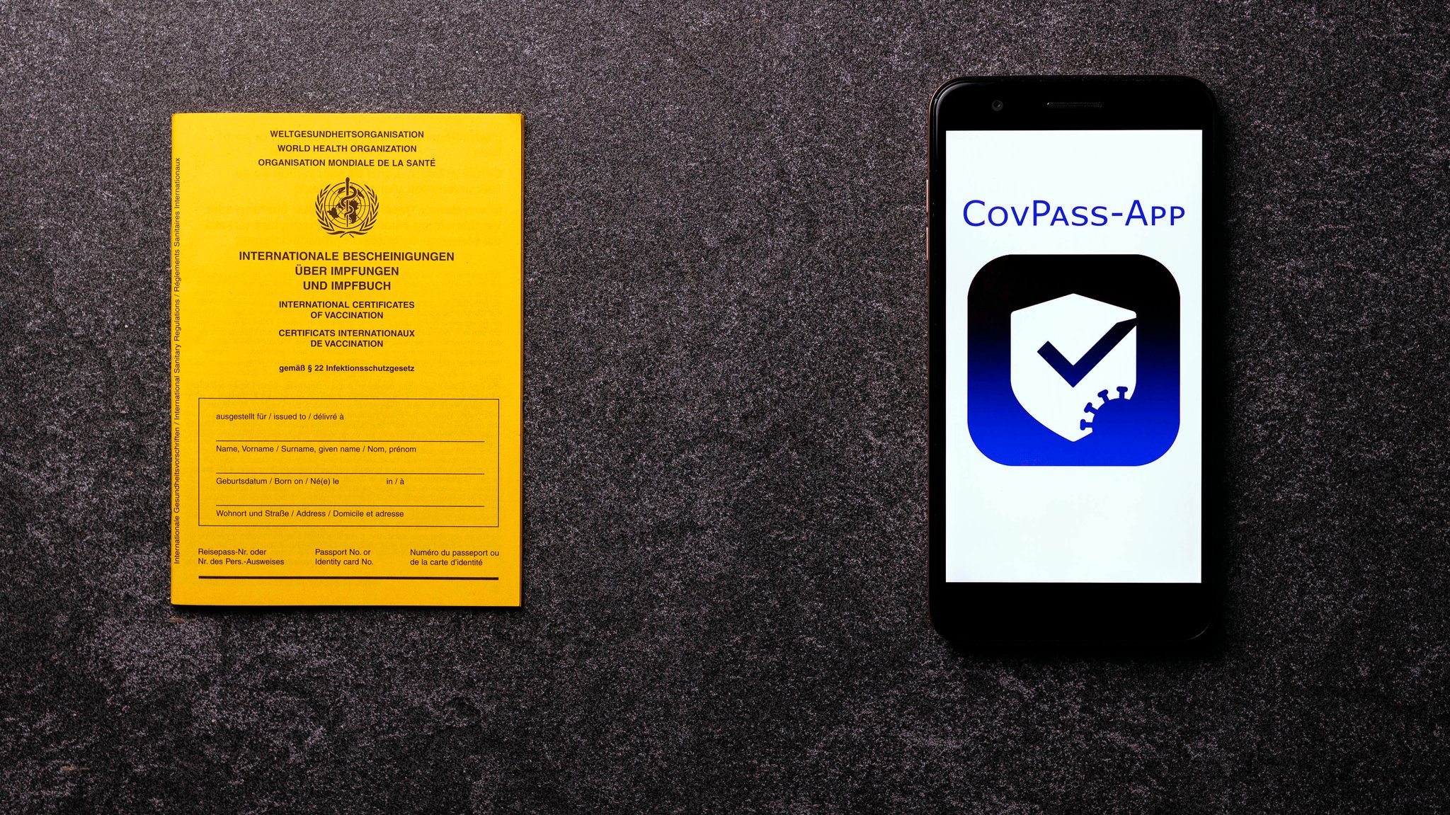 Die in Deutschland geplante "CovPass-App" auf einem Smartphone-Bildschirm neben einem traditionellen Impfausweis, aufgenommen am 28.05.21.