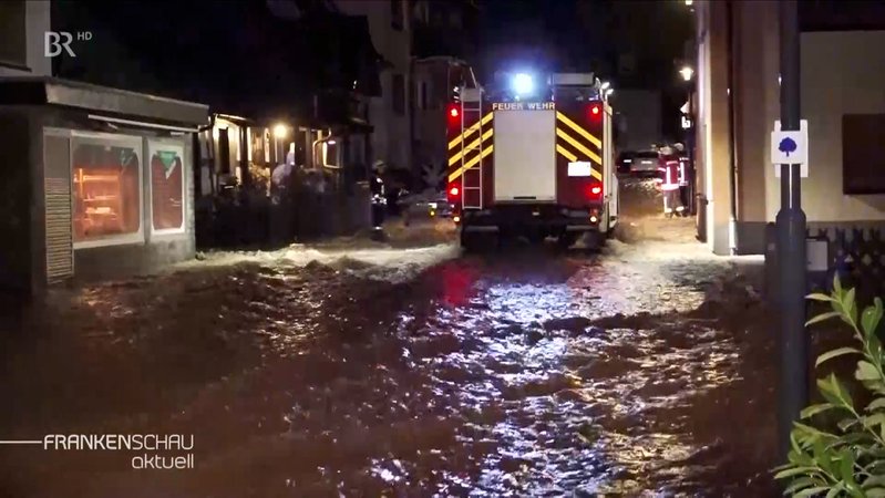 Feuerwehrauto in überfluteter Straße.