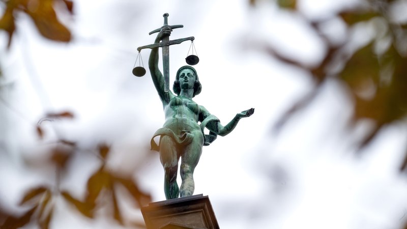 Hinter herbstlich verfärbten Blättern steht eine Statue der Justitia auf dem Gebäude des Landgerichts Bamberg. | Bild: picture alliance/dpa | Pia Bayer Hinter herbstlich verfärbten Blättern steht eine Statue der Justitia auf dem Gebäude des Landgerichts Bamberg.