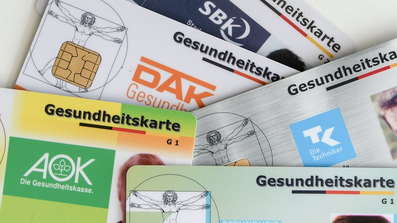 Archiv: Gesundheitskarten verschiedener Krankenkassen liegen auf einem Tisch (Symbolbild) | Bild: dpa-Bildfunk/Jens Kalaene Archiv: Gesundheitskarten verschiedener Krankenkassen liegen auf einem Tisch (Symbolbild)