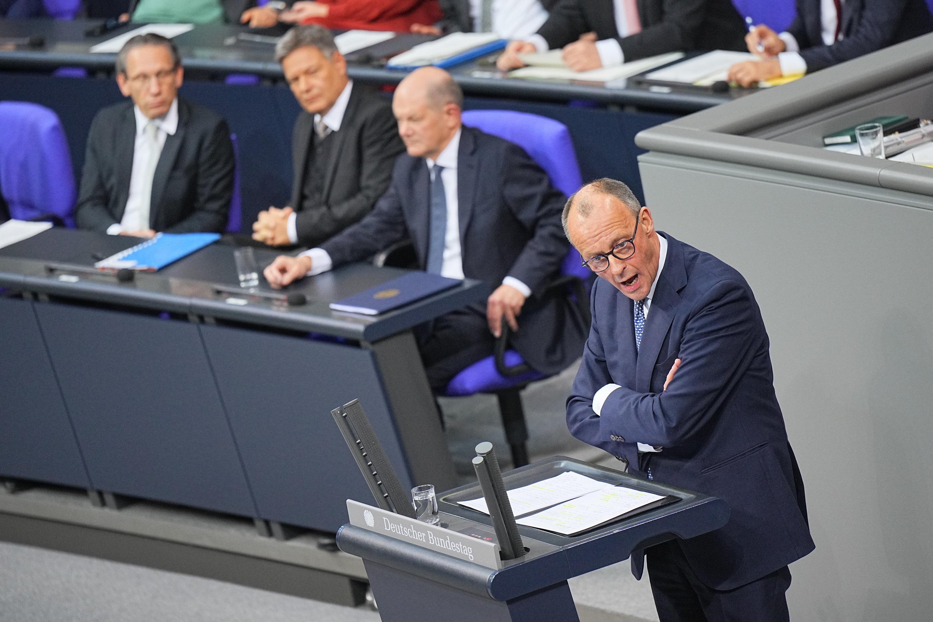 Merz spricht im Bundestag, dahinter sitzen Scholz und Habeck
