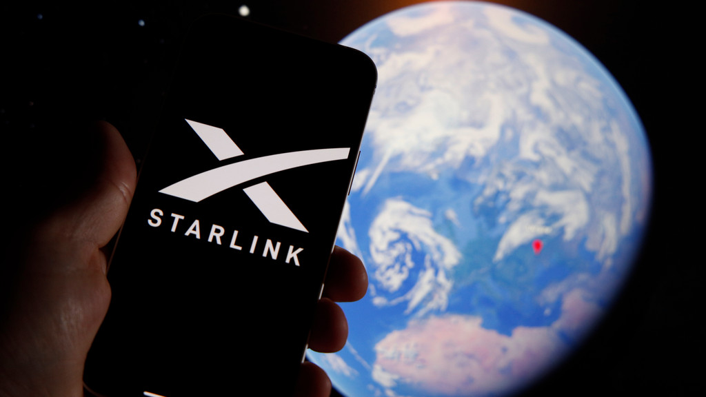 The Starlink logo is seen on a mobile device with an grahpic illustration of planet Earth