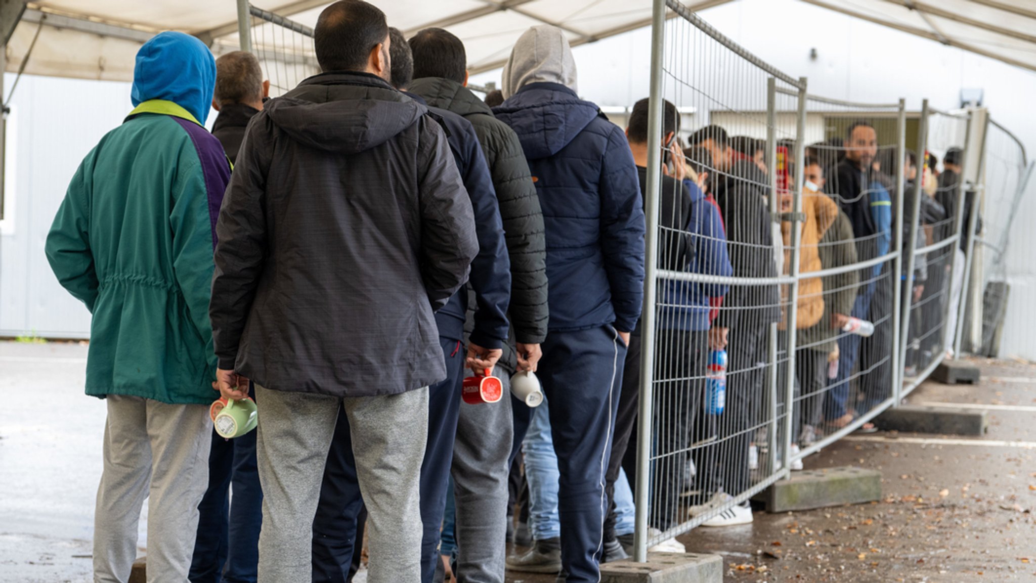 Symbolbild: Flüchtlinge warten in einer Schlange vor der Essensausgabe.