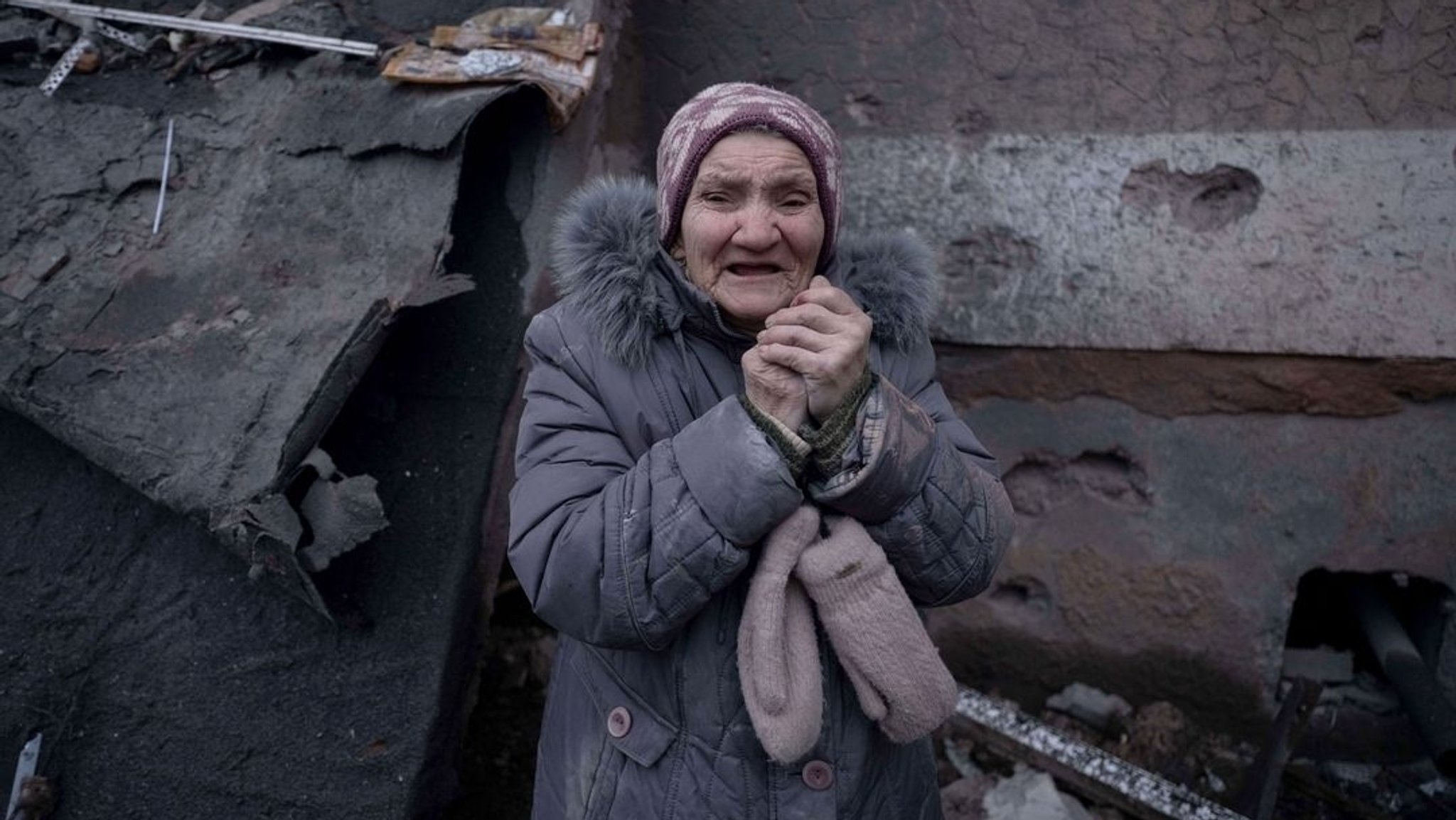 Eine ukrainische Frau weint vor einem zerstörten Gebäude