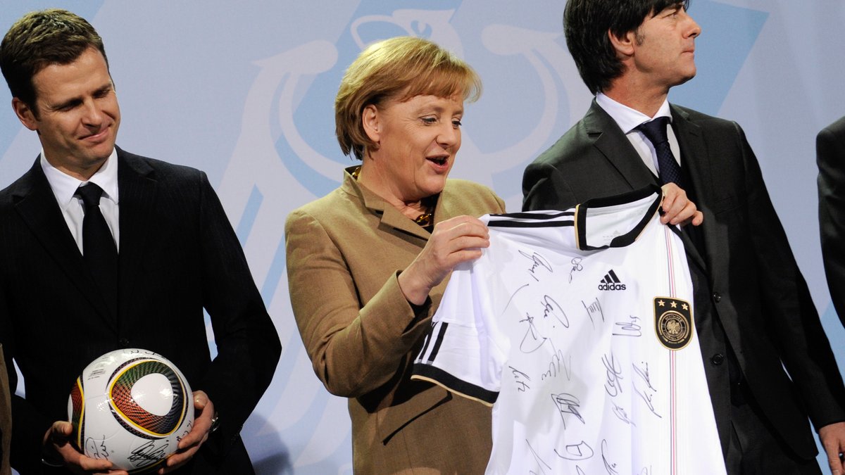Archivbild 2010: Angela Merkel hält ein von den Spielern unterzeichnetes Fußball-Trikot für die WM 2010 in Südafrika. 
