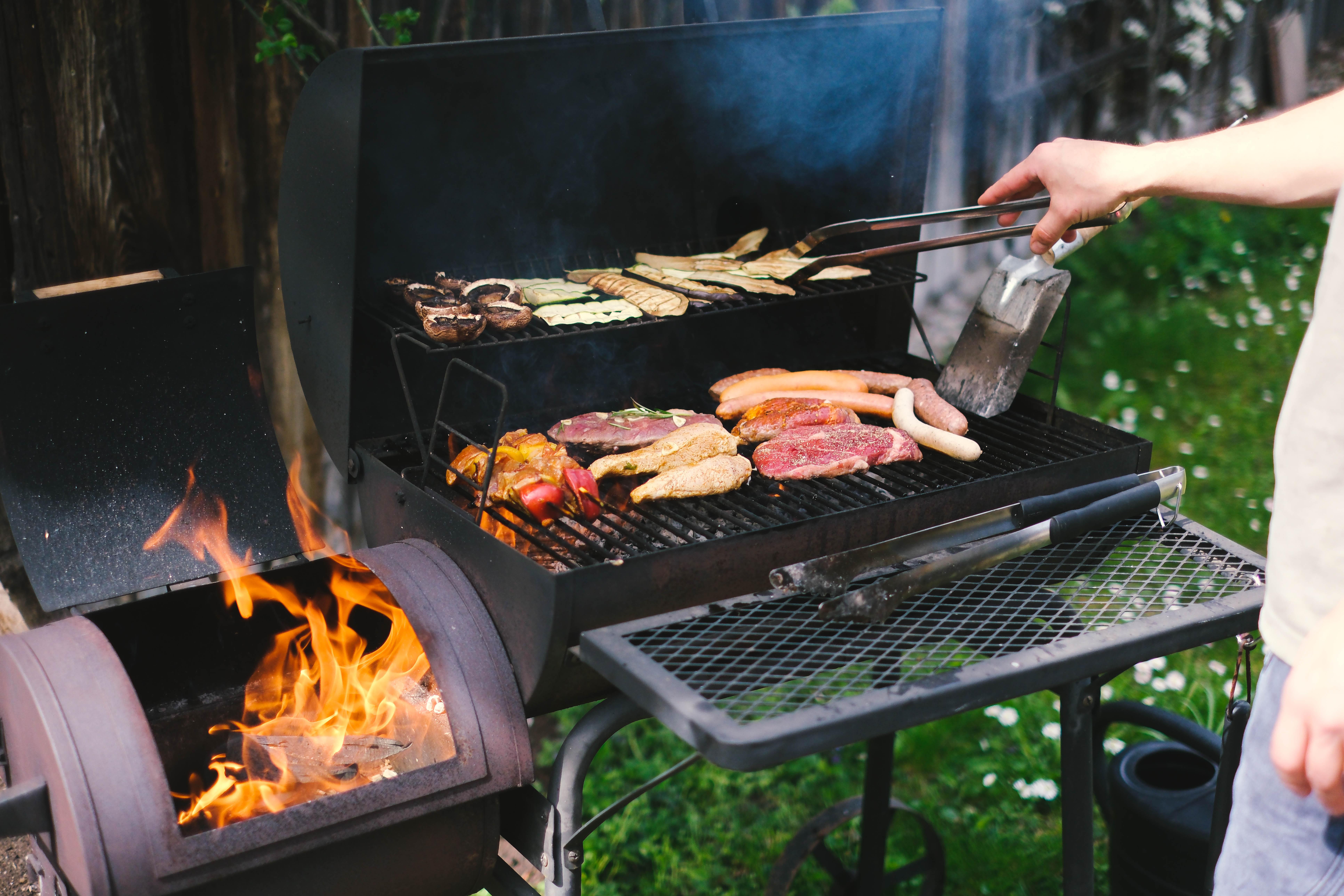 Ein Mann grillt Fleisch und Gemüse. 