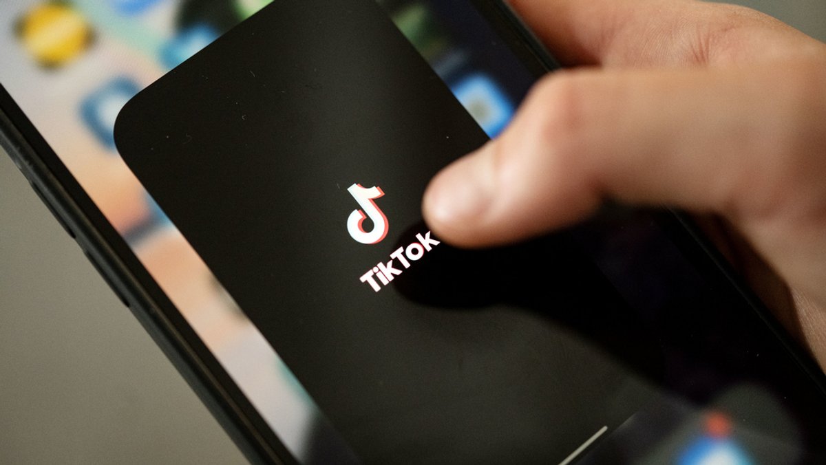 Ein Teenager tippt auf das TikTok-Logo auf einem Smartphone. 