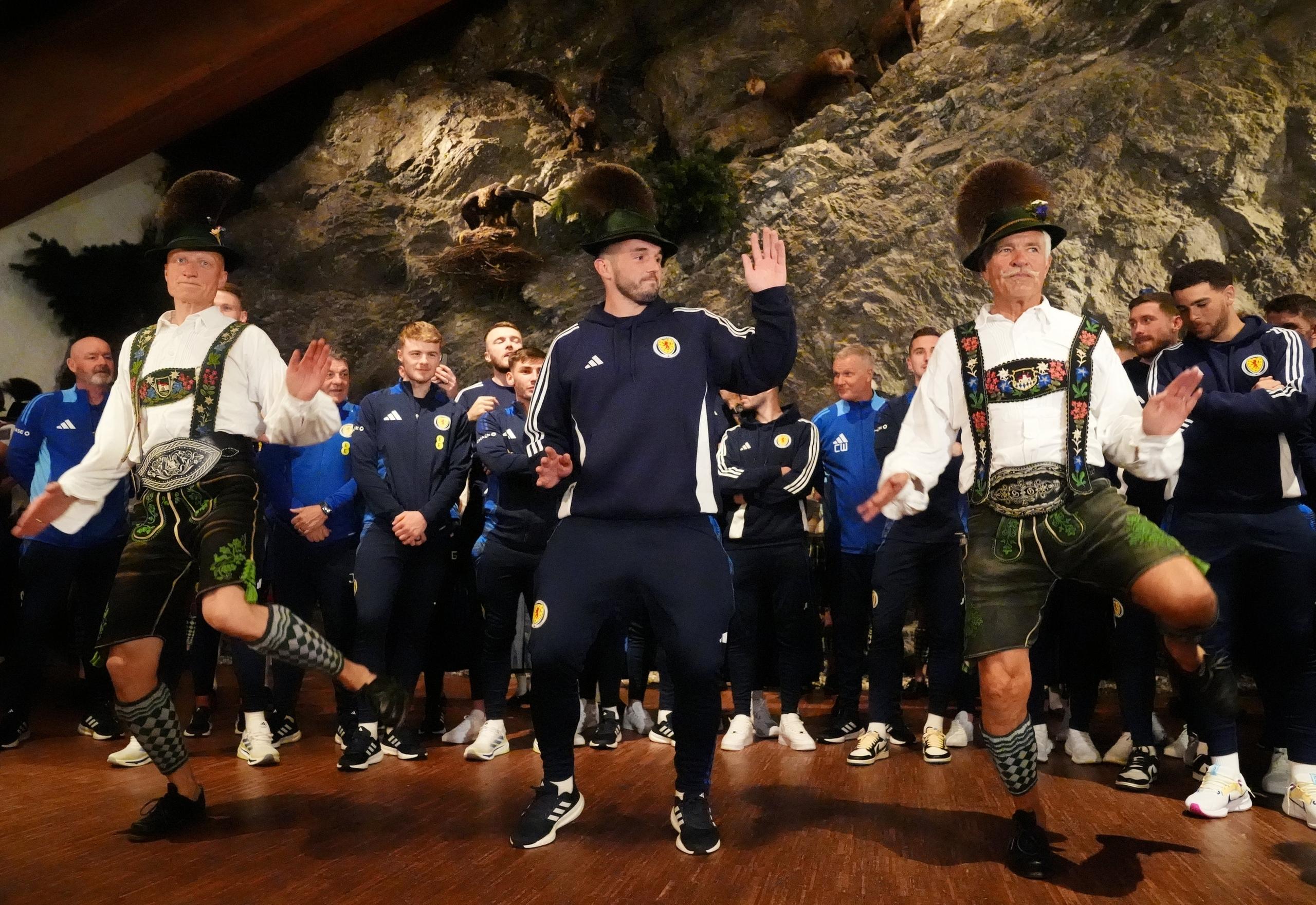dpatopbilder - 09.06.2024, Bayern, Garmisch-Partenkirchen: Fußball: EM, Gruppe A, Schottland, Ankunft im Teamquartier. Schottlands John McGinn (M) tanzt mit, als die Mannschaft in der Bayernhalle zu einem Empfang des Bürgermeisters eintrifft.