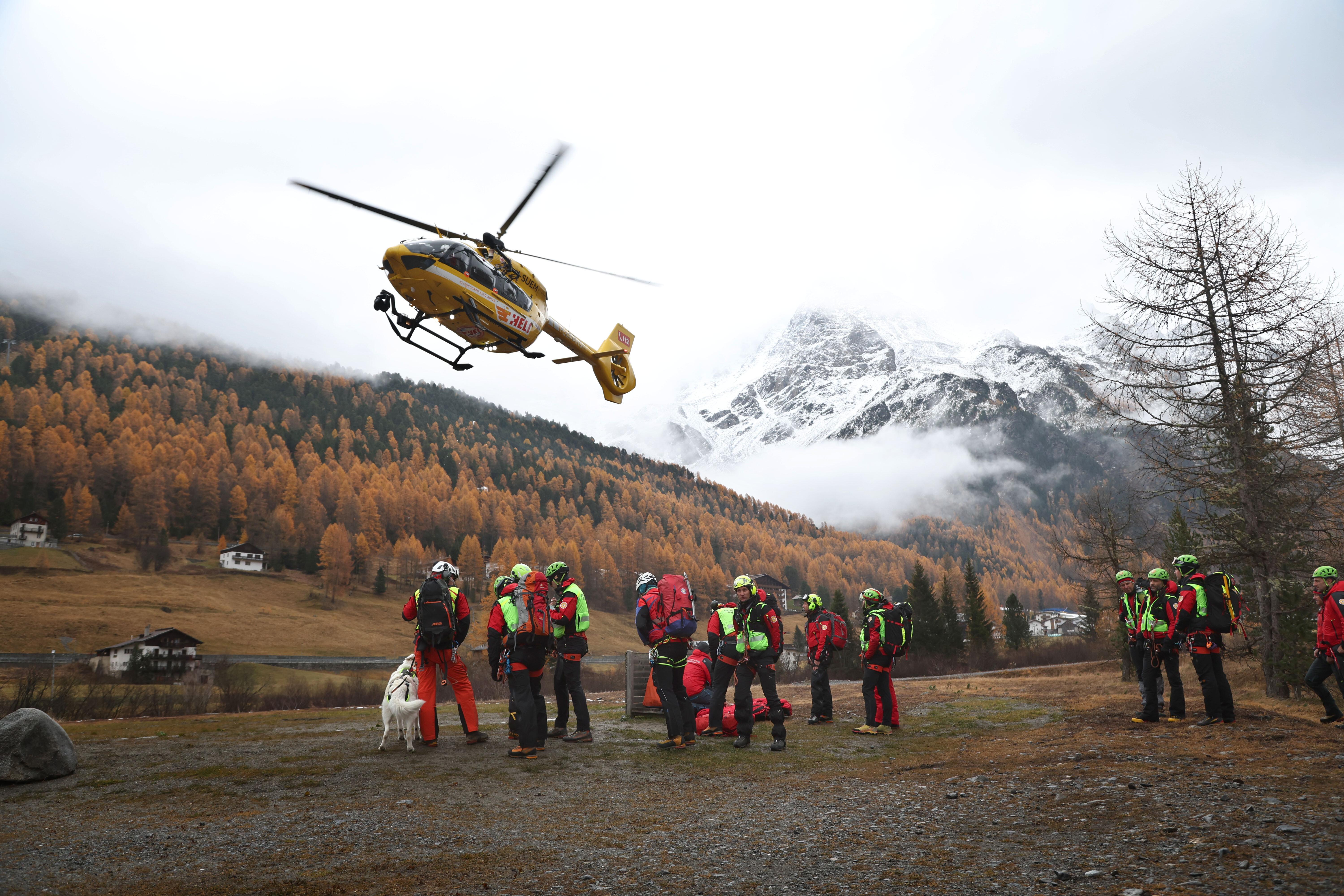 Ein Hubschrauber der Bergrettung landet vor Bergrettern. 