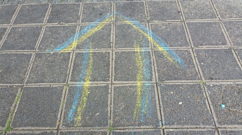 Blau-gelber Pfeil auf einem Bürgersteig.