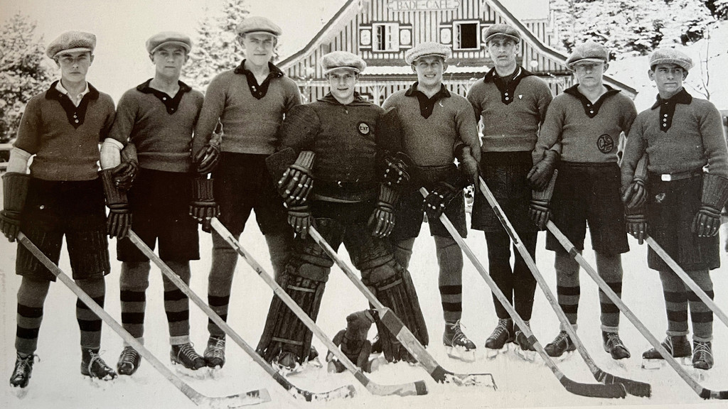 Ein Schwarzweißfoto zeigt die 1b-Mannschaft des EV Füssen auf der Eisfläche des Mittersees in Bad Faulenbach in den 1920er-Jahren.