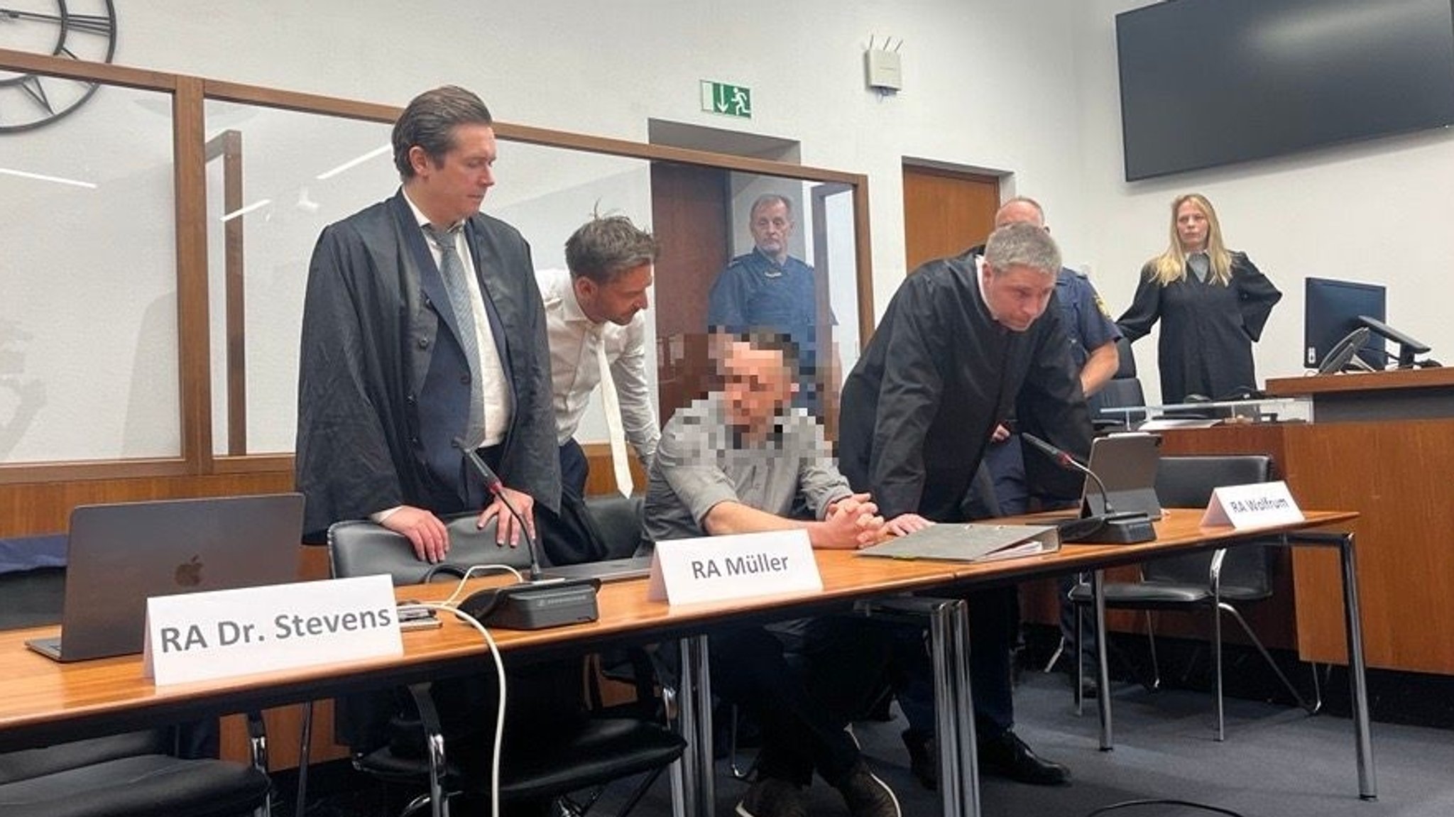 Der Angeklagte sitzt in einem Gerichtssaal, neben ihm stehen mehrere Anwälte. | Bild: BR24/Annerose Zuber Der Angeklagte sitzt in einem Gerichtssaal, neben ihm stehen mehrere Anwälte.
