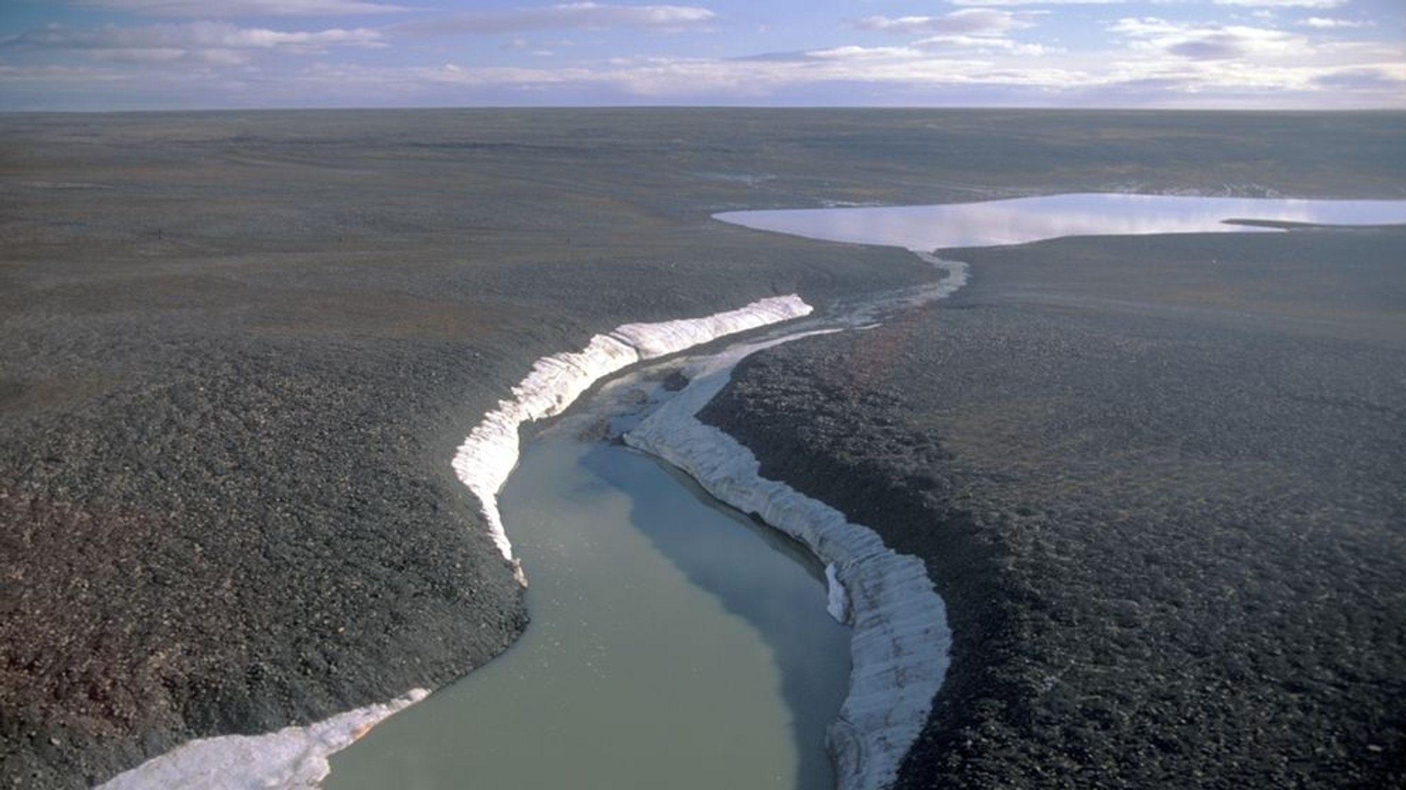 Tundra-Landschaft mit einem Schmelzwasser führenden Fluss auf der russischen Bolschewik Insel (Sibirien).