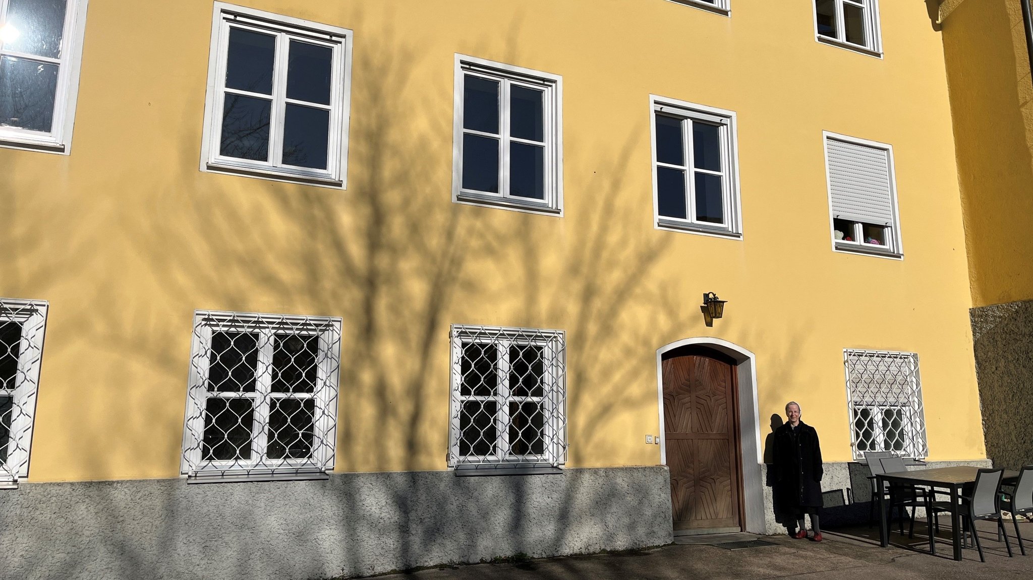 Klosterschwester steht vor gelbem Klostergebäude mit weißen Fenstern in Medingen.