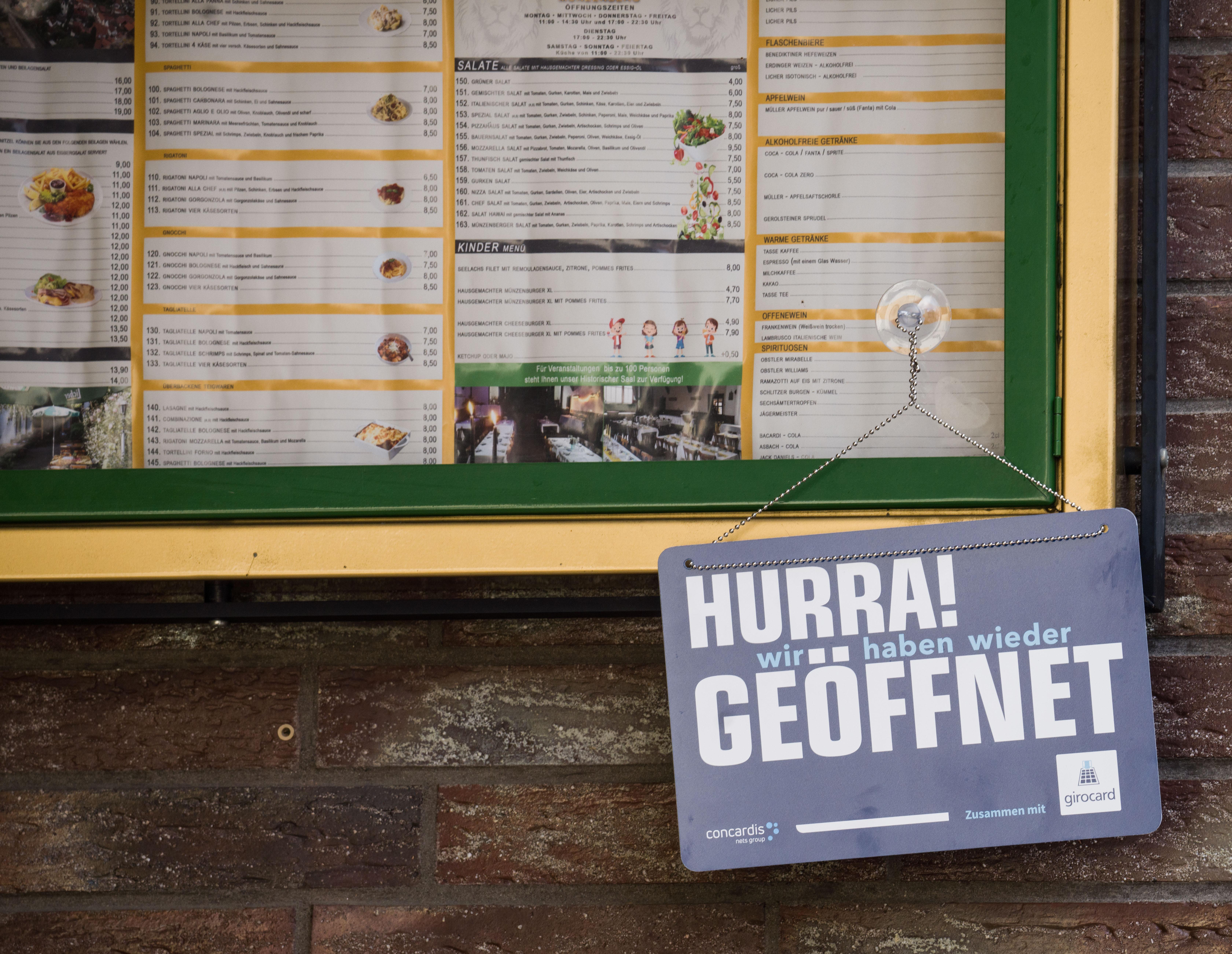 "Hurra! Wir haben wieder geöffnet" steht auf einem Schild unterhalb der Speisekarte einer Gaststätte.