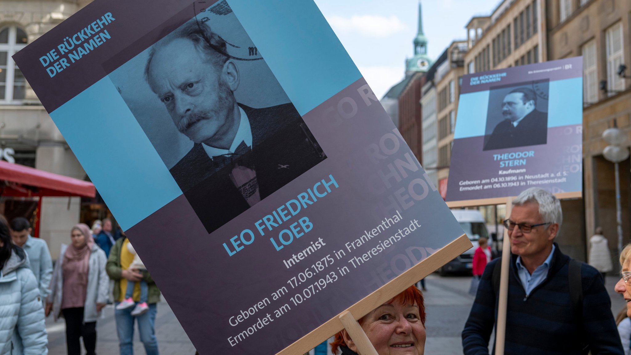 Teilnehmer des Erinnerungsprojekts "Die Rückkehr der Namen" treffen sich mit ihren Plakaten in der Innenstadt.