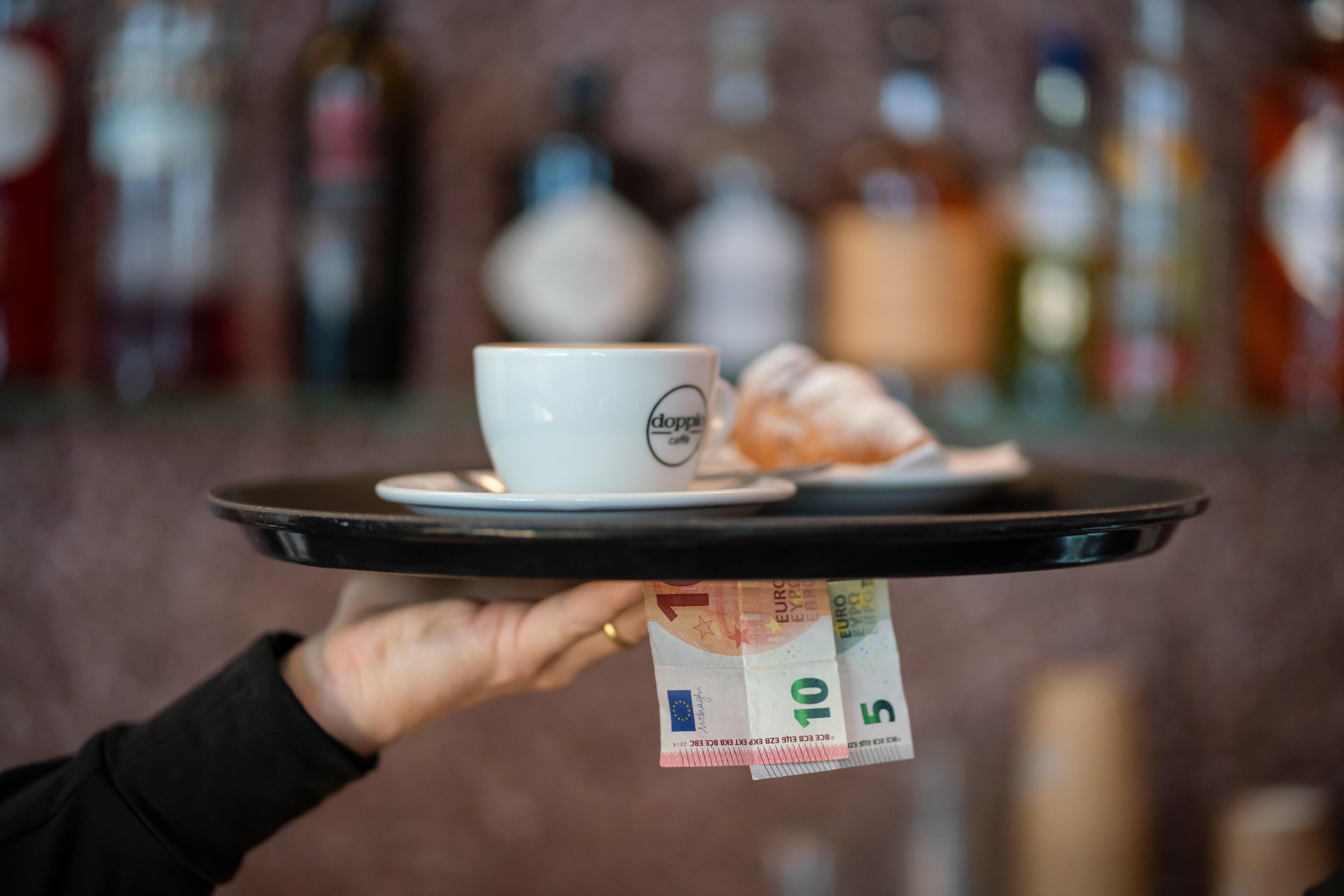 Eine Hand mit Tablette und Geldscheinen