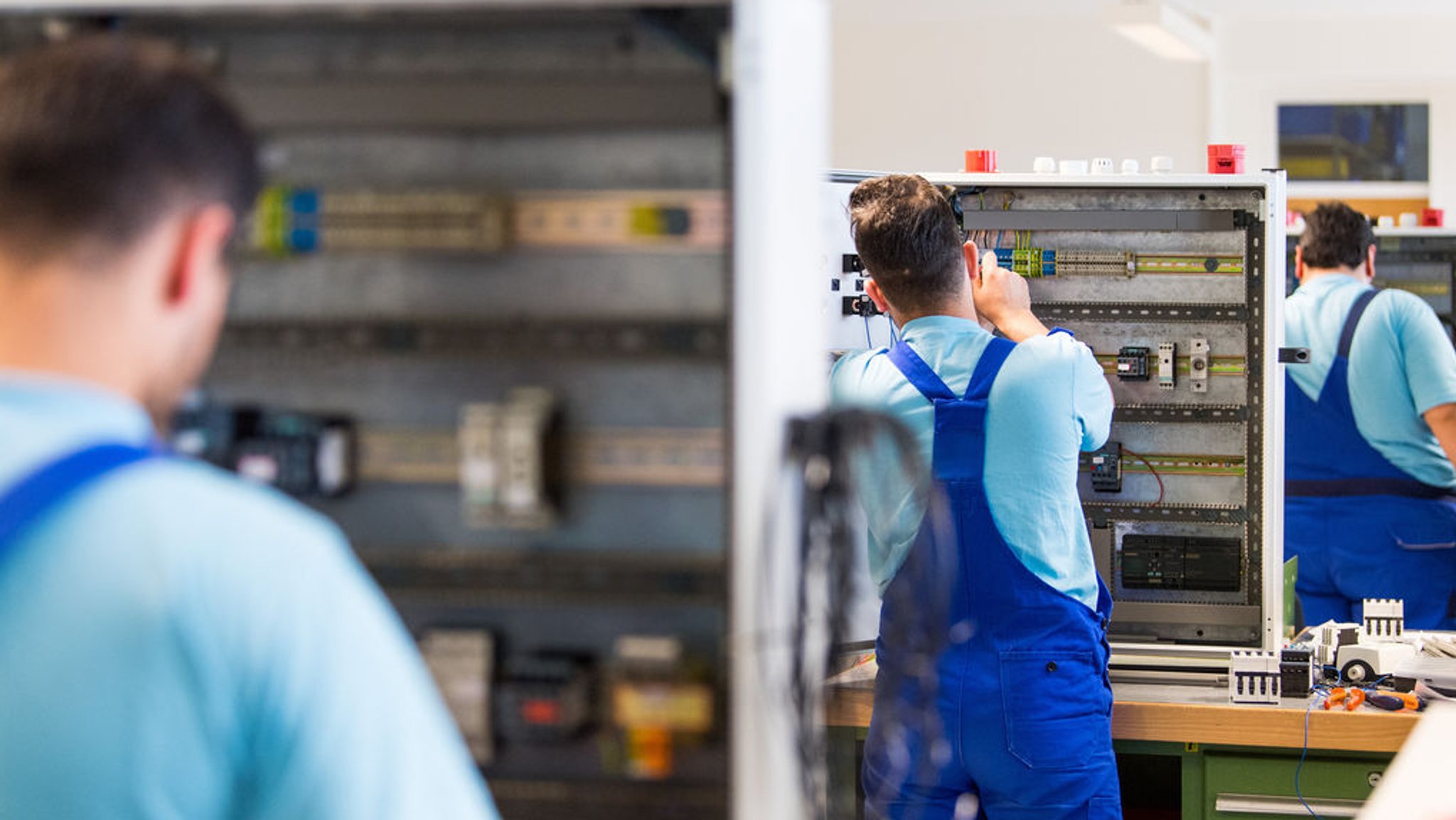 Flüchtlinge arbeiten im Ausbildungszentrum der Siemens Professional Education an der Verdrahtung eines Schaltschranks.