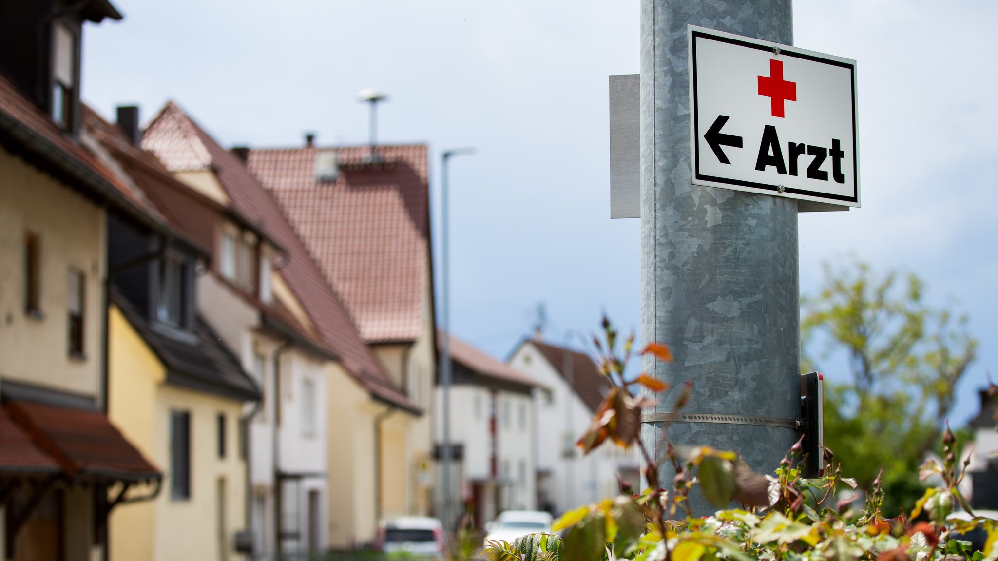 Ein Schild mit der Aufschrift "Arzt" hängt an einer Straßenlaterne.