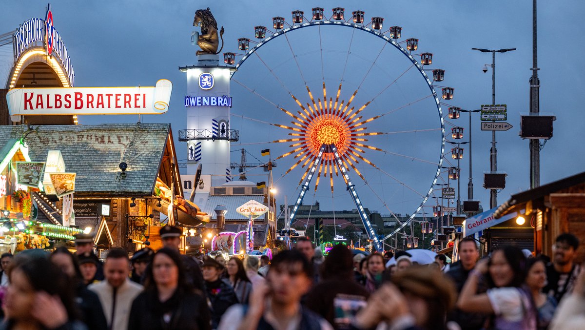 Besucher des Oktoberfestes gehen über das Festgelände